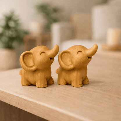 Zwei identische Elefanten-Miniaturen aus Holz, die beide nach rechts schauen und ihre Rüssel fröhlich nach oben strecken.