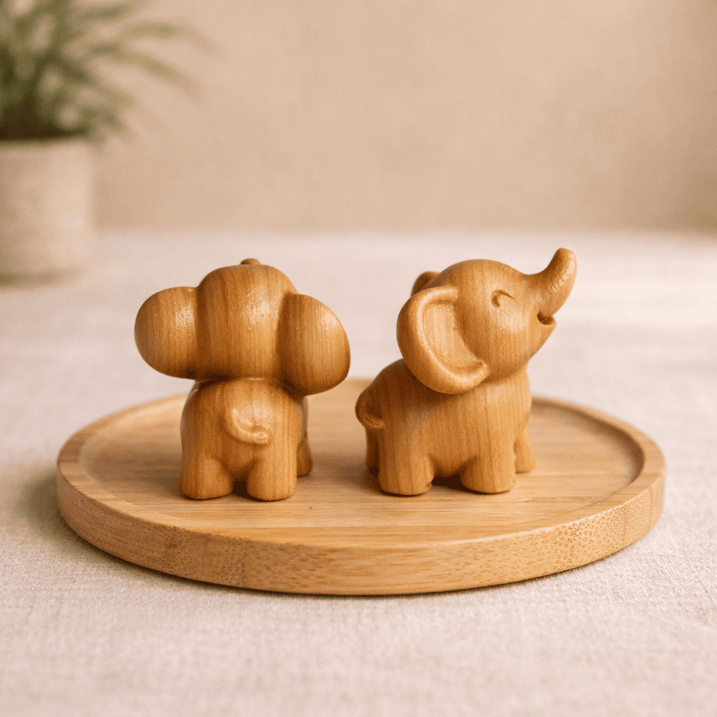 Detailansicht der Holz-Elefanten von vorne und hinten auf einem runden Holztablett, die die feine Maserung und das Schwänzchen zeigen.
