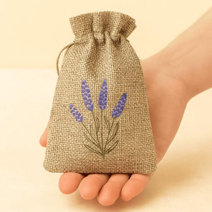 Natürliches Lavendel-Duftsäckchen aus Jute mit Lavendelmotiv, dekorativ in einer Hand präsentiert, nachhaltiger Raumduft im minimalistischen Naturstil.
