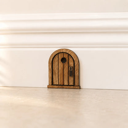 Kleine Mäusetür aus Holz an weißer Fußleiste als dekorative Wohndeko